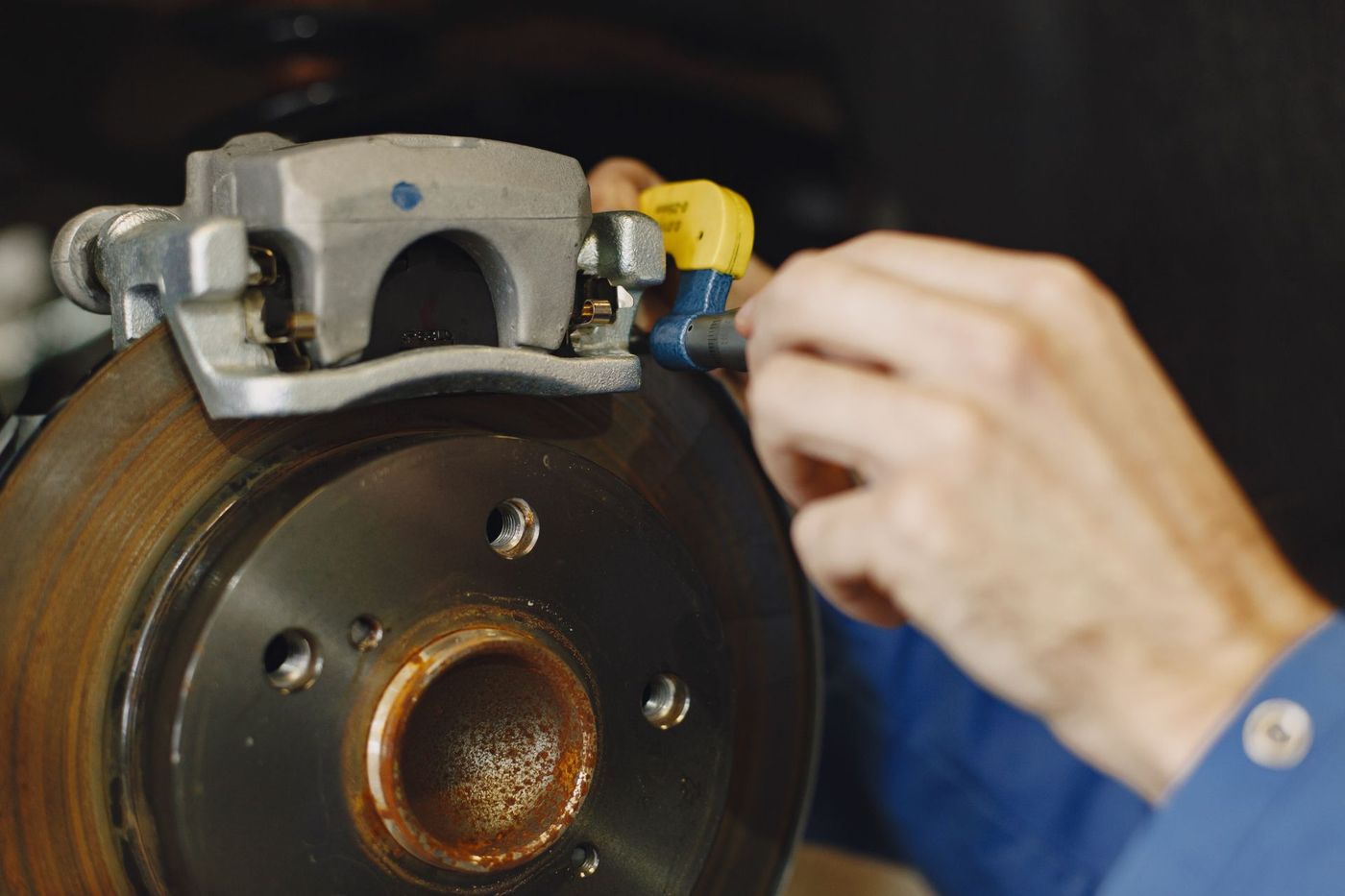 Gloved hand working on a disc brake and caliper with the wheel removed